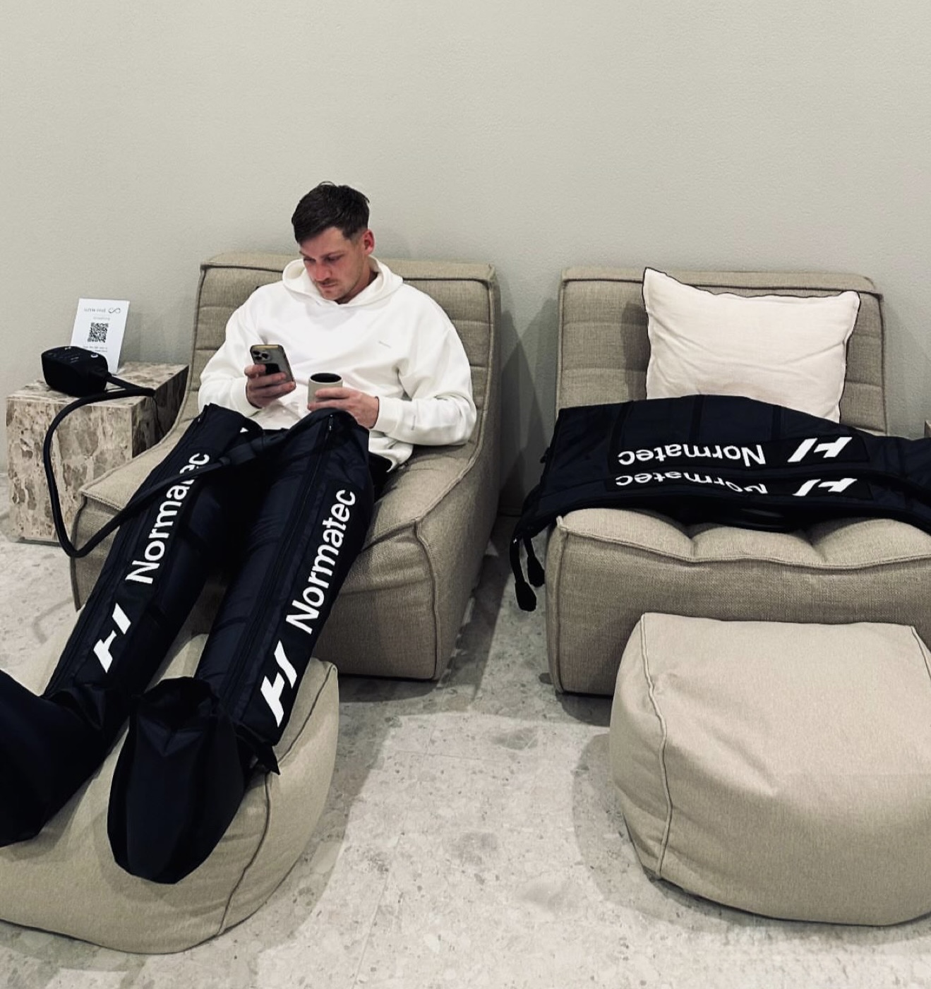 A client relaxing in Normatec compression leg sleeves in the lounge