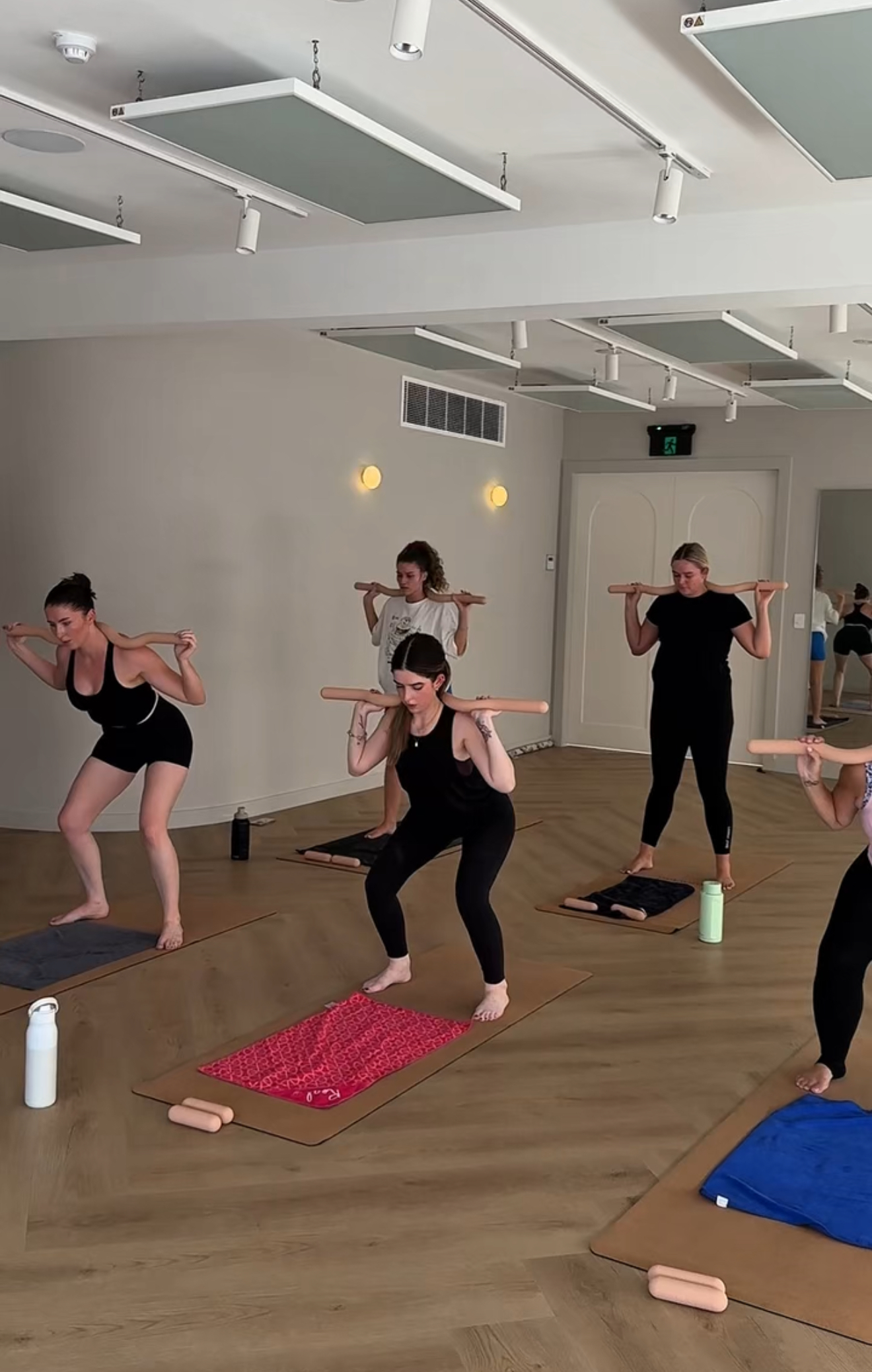A class squatting with weighted bars across their shoulders in the studio